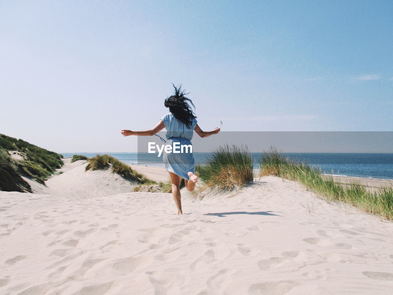 REAR VIEW OF WOMAN WALKING ON BEACH