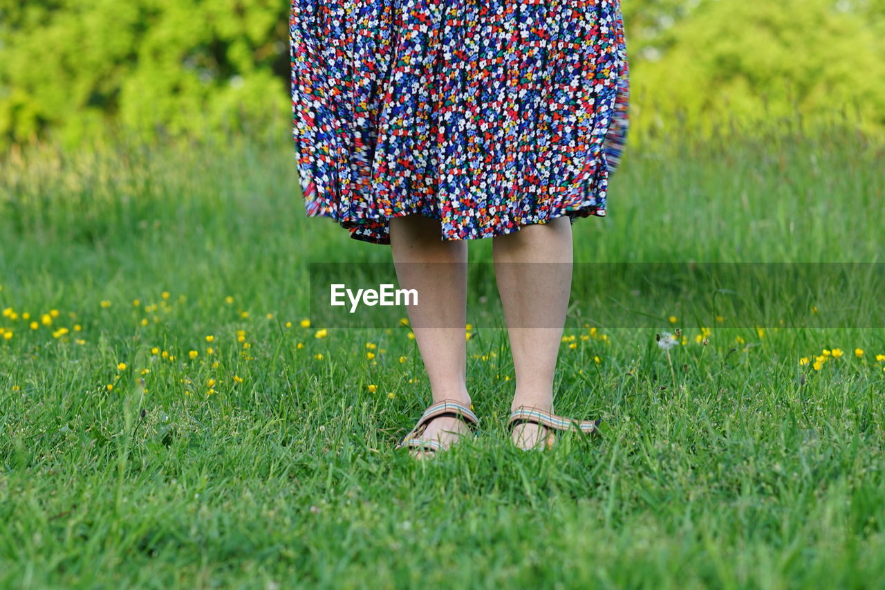 Woman with flower skirt close up bare legs in gras spring summer