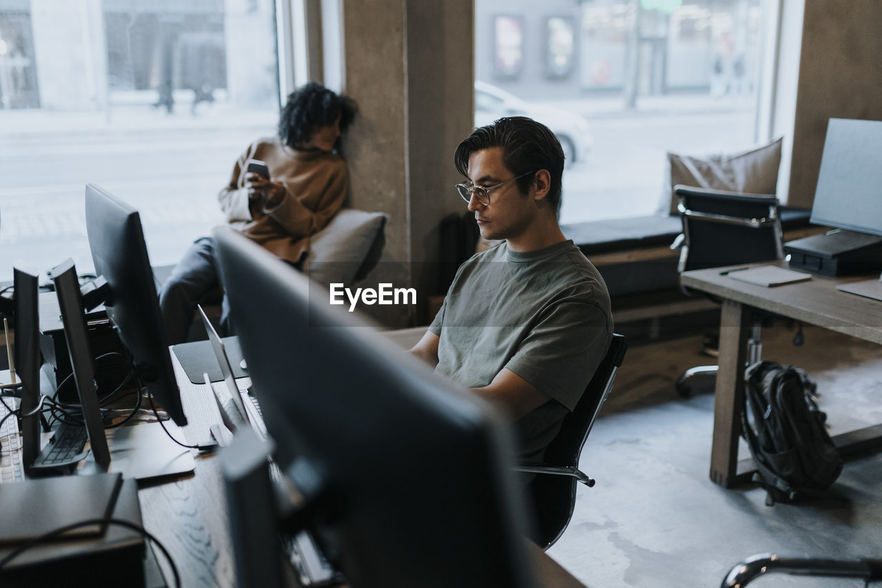 Young businessman working on laptop at desk in creative office