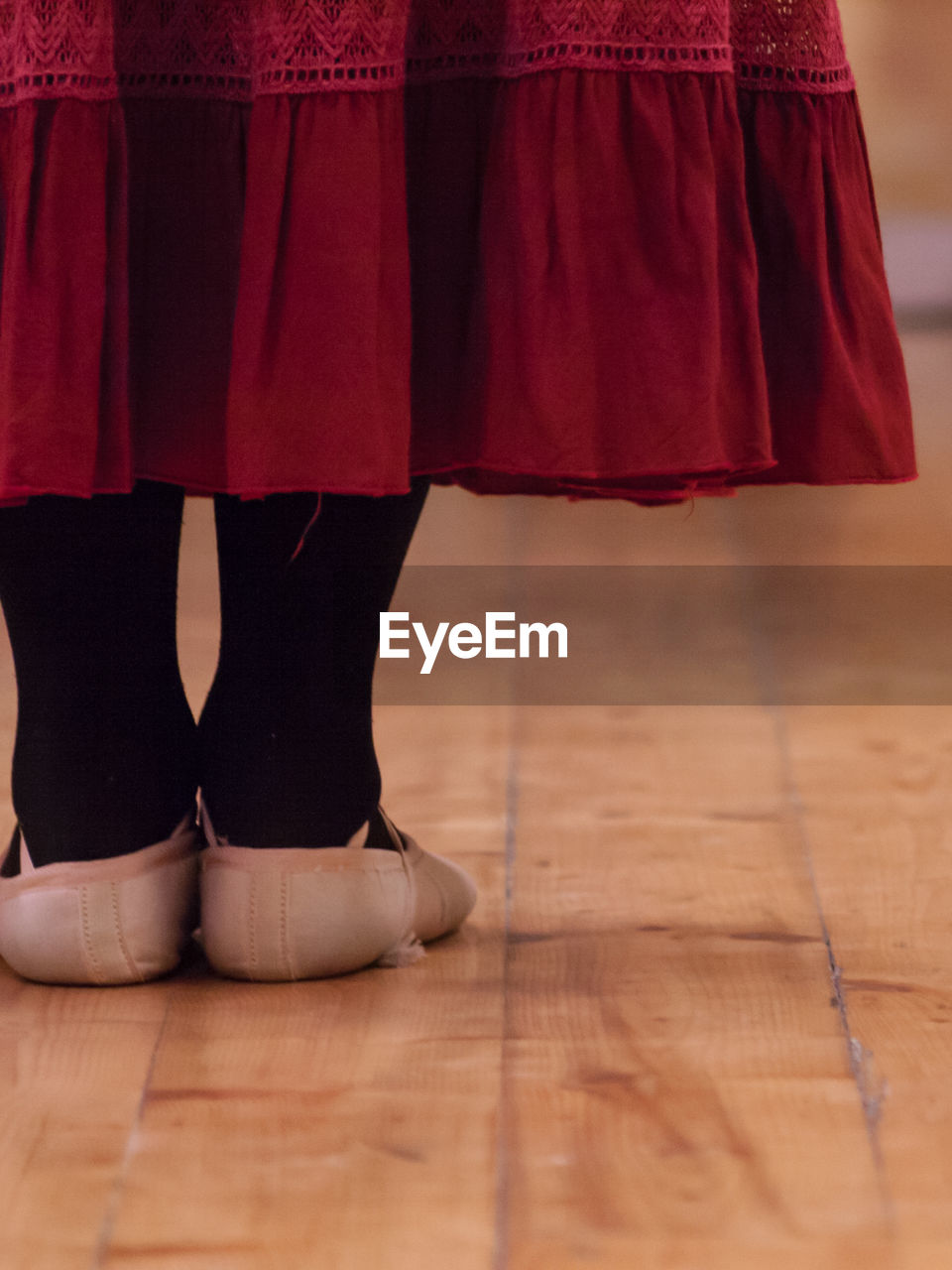 LOW SECTION OF WOMAN STANDING ON HARDWOOD FLOOR IN BEDROOM