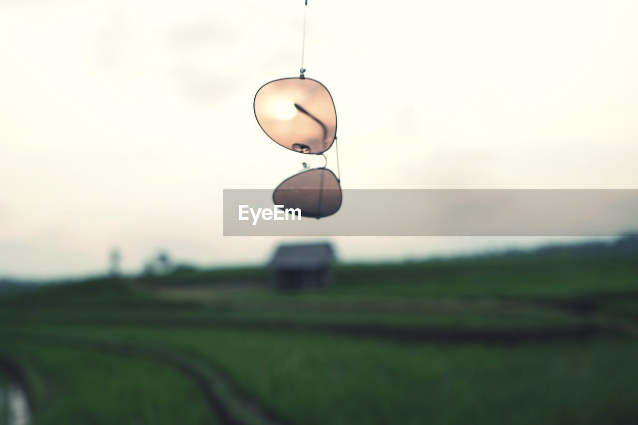 Close-up of sunglasses over field against sky