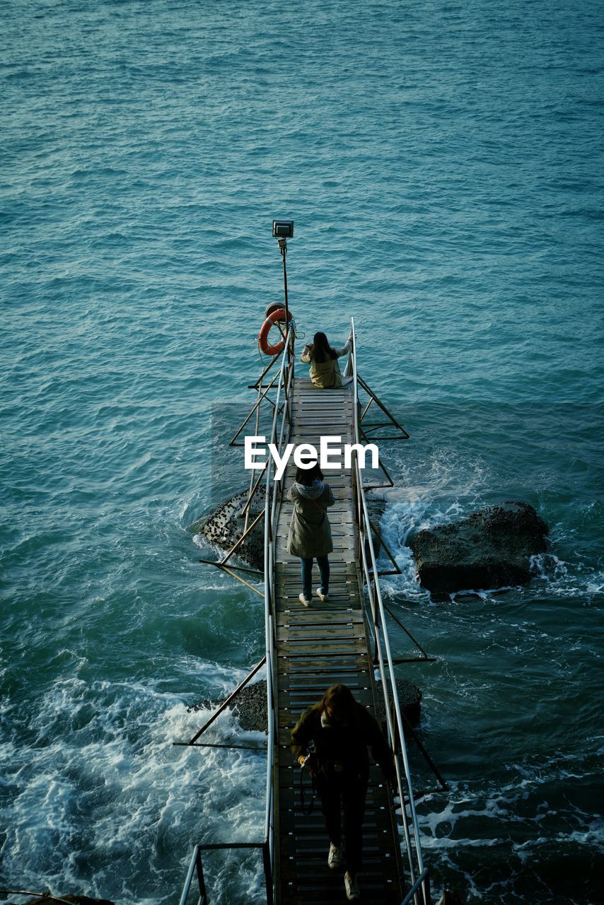 High angle view of girl standing on pier over sea