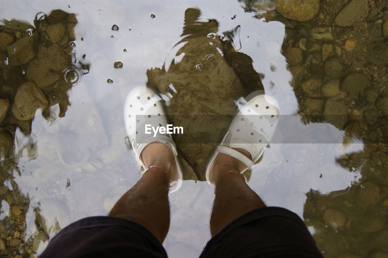 Low section of man standing in lake