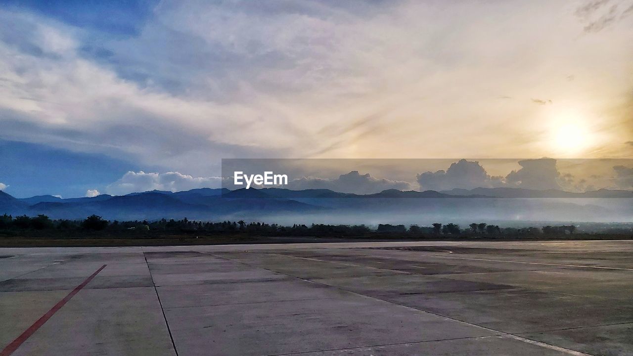 sky, horizon, cloud, environment, mountain, nature, travel, plain, airport runway, morning, airport, landscape, no people, scenics - nature, dawn, transportation, airplane, sunrise, beauty in nature, air vehicle, mountain range, outdoors, sun, tranquility, travel destinations, land, road, sunlight