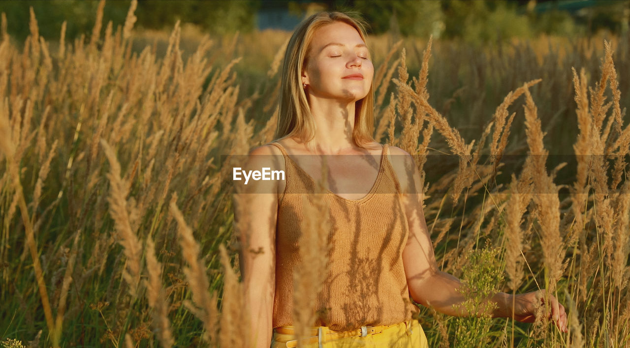 portrait of smiling young woman standing amidst plants