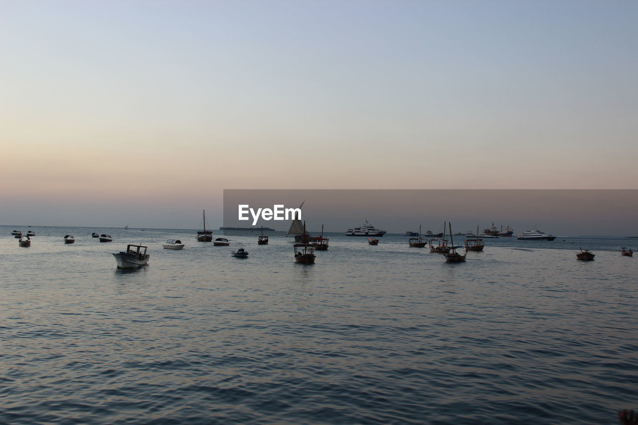Boats anchored on sea at dusk