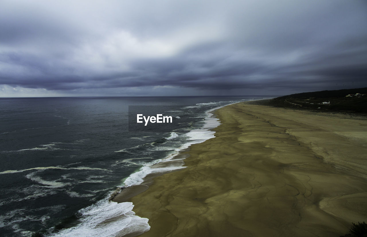 Scenic view of sea shore against cloudy sky 