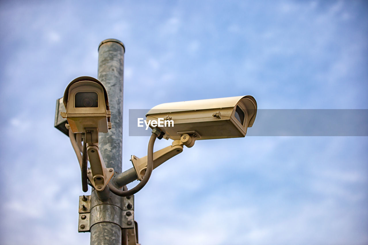 Close-up of security camera on pole against sky