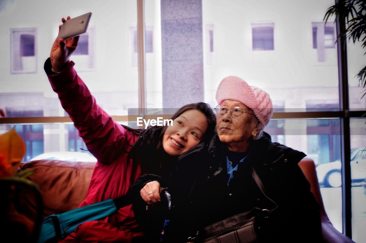 Smiling mid adult woman taking selfie with mother 