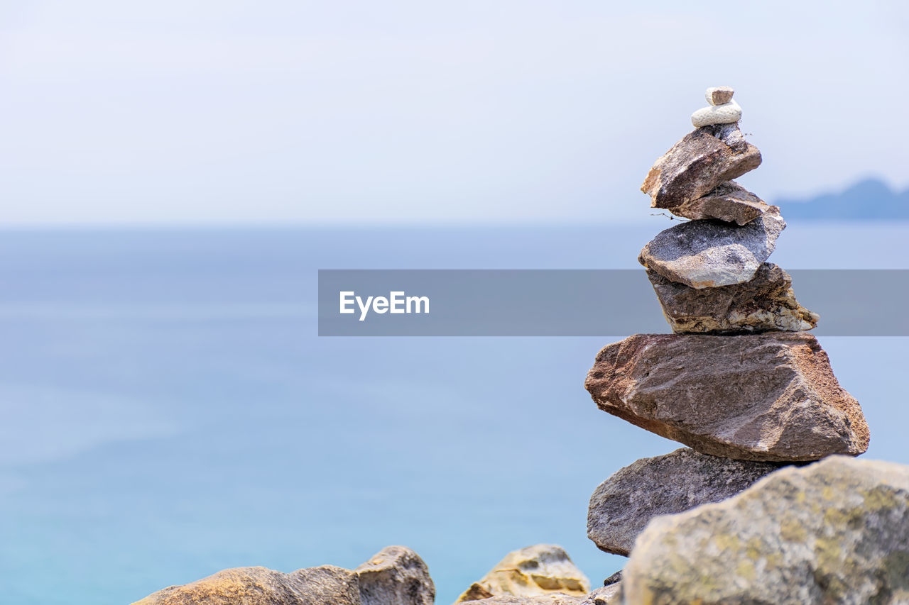 Stack of rocks in sea against sky