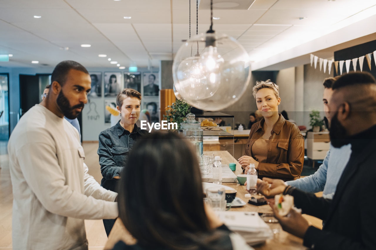 Male and female professionals discussing during meeting at cafeteria in office