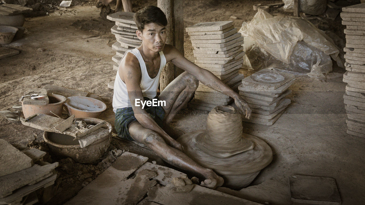 HIGH ANGLE VIEW OF MAN WORKING ON TOP OF MUD