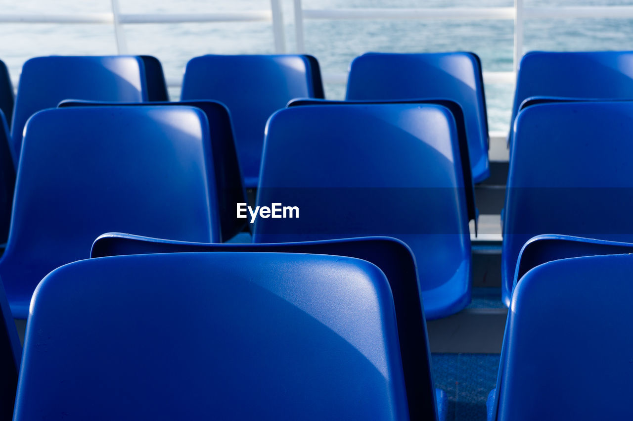 Rows of empty blue ferry boat seats