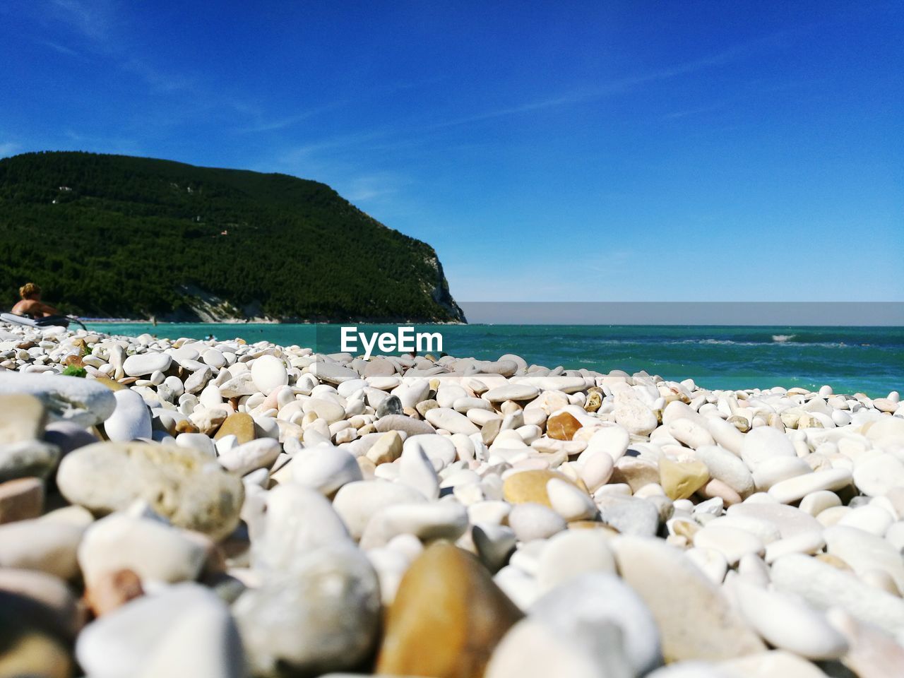 SURFACE LEVEL OF PEBBLE BEACH AGAINST BLUE SEA