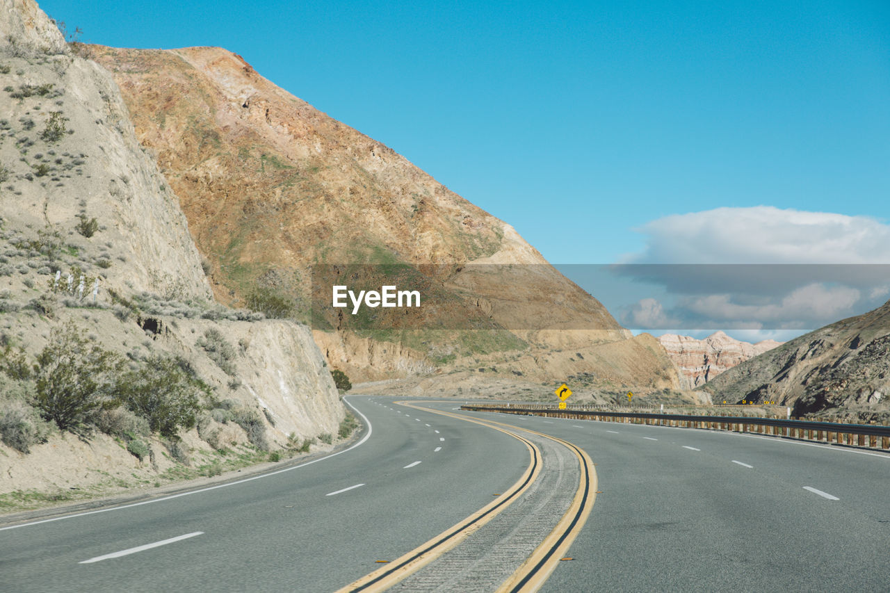 Empty road by mountains against sky