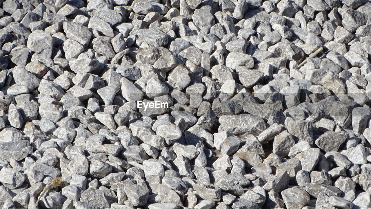 full frame, backgrounds, gravel, rubble, large group of objects, abundance, asphalt, textured, no people, stone, rock, day, road surface, stone wall, pattern, soil, flooring, high angle view, wall, gray, nature, outdoors, sunlight, cobblestone, rough, pebble, close-up, directly above, land