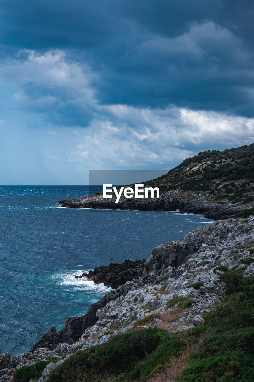 SCENIC VIEW OF ROCKY BEACH AGAINST SKY