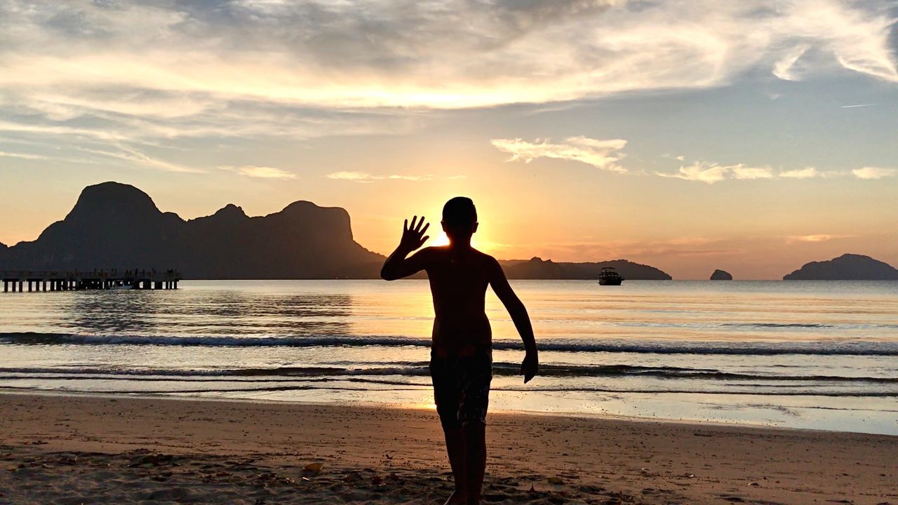 SILHOUETTE MAN STANDING AT BEACH DURING SUNSET