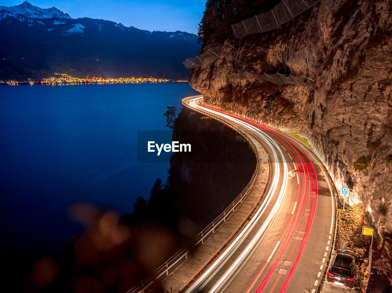 HIGH ANGLE VIEW OF LIGHT TRAILS ON ROAD BY MOUNTAIN