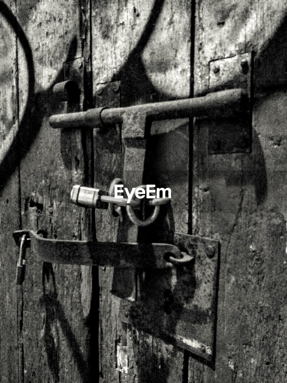 CLOSE-UP OF PADLOCKS ON METAL ATTACHED TO METALLIC WALL