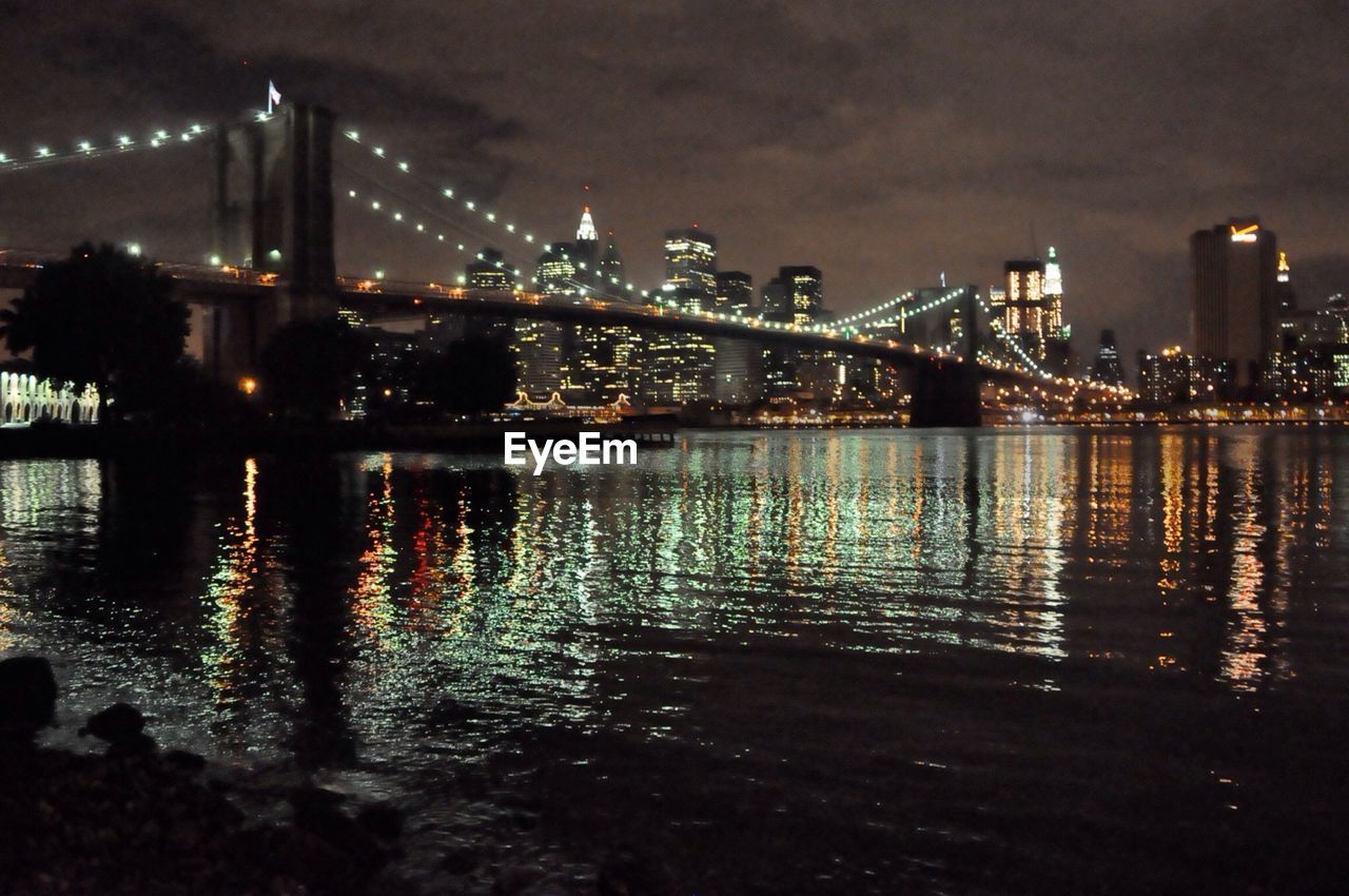 ILLUMINATED BRIDGE OVER RIVER AT NIGHT
