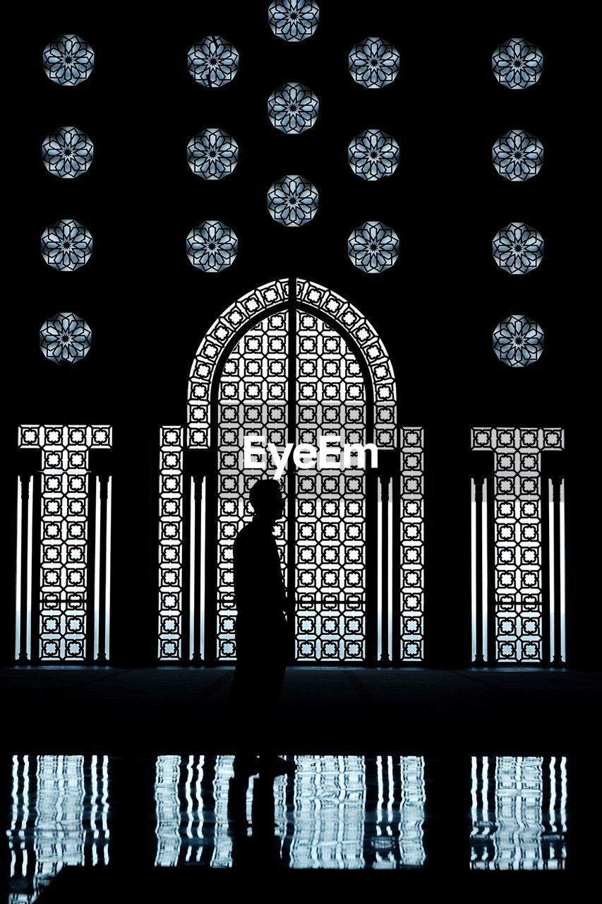 Silhouette man standing against window with reflection on floor at mosque hassan ii