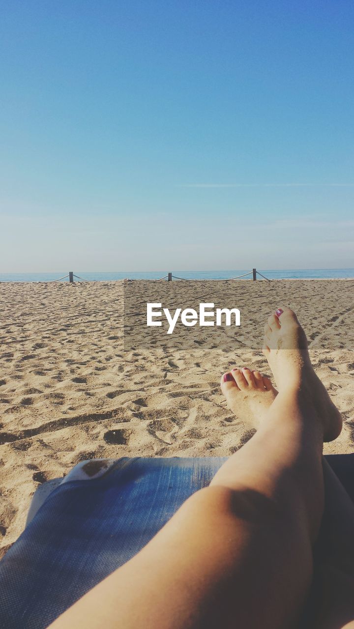 LOW SECTION OF WOMAN RELAXING ON BEACH