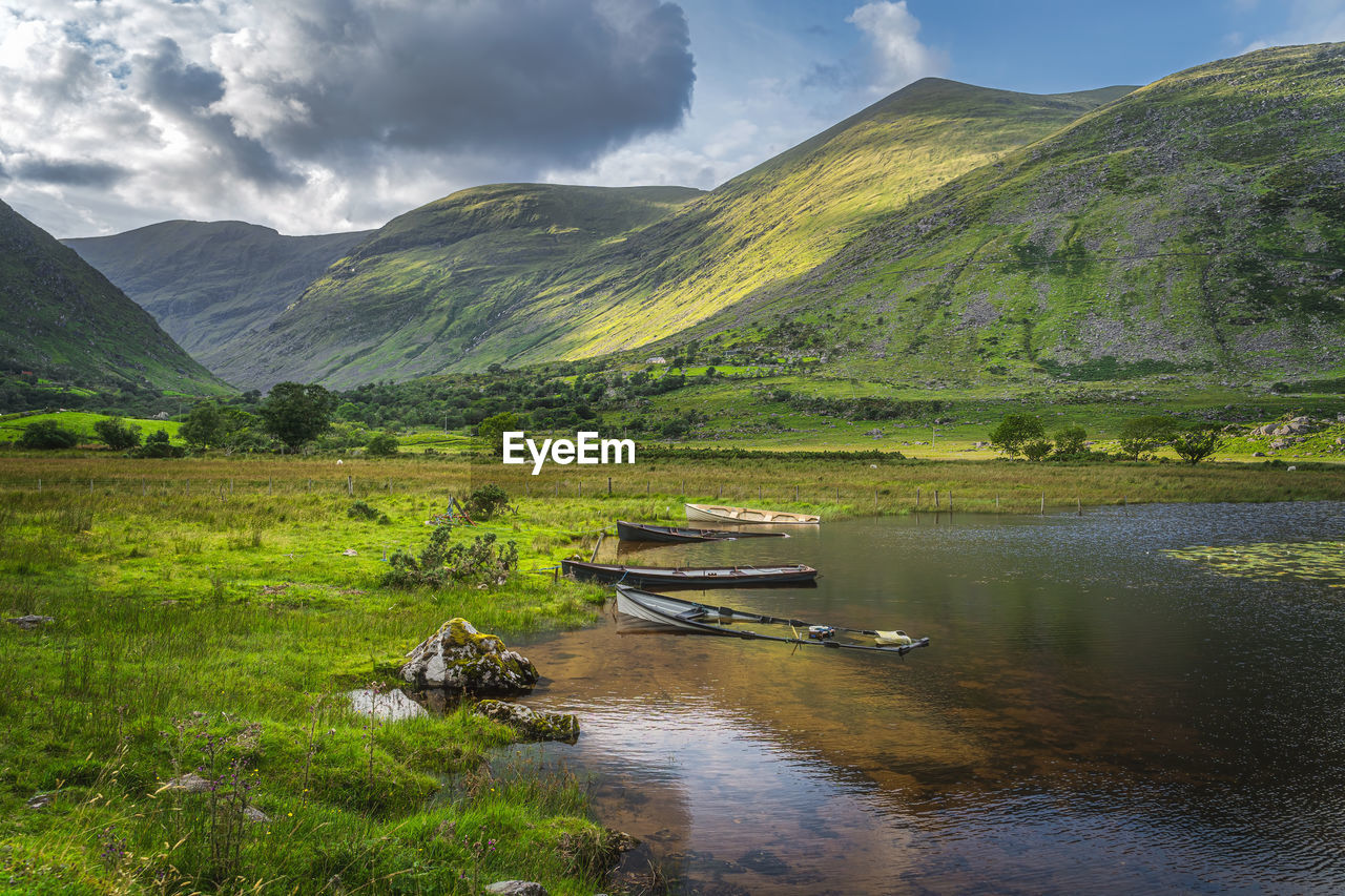 Sunken paddle boats in lough gummeenduff with sunlight on hills in beautiful black valley, ireland