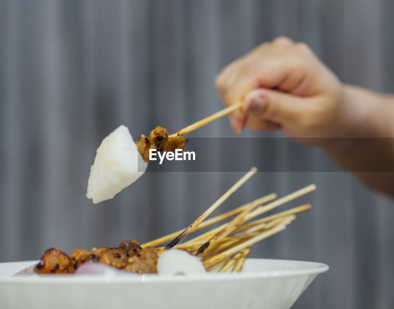 Satay on stick with rice hand holding ketupat