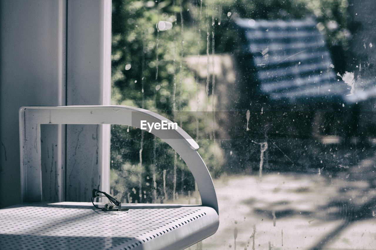 Eyeglasses on chair against dirty glass window