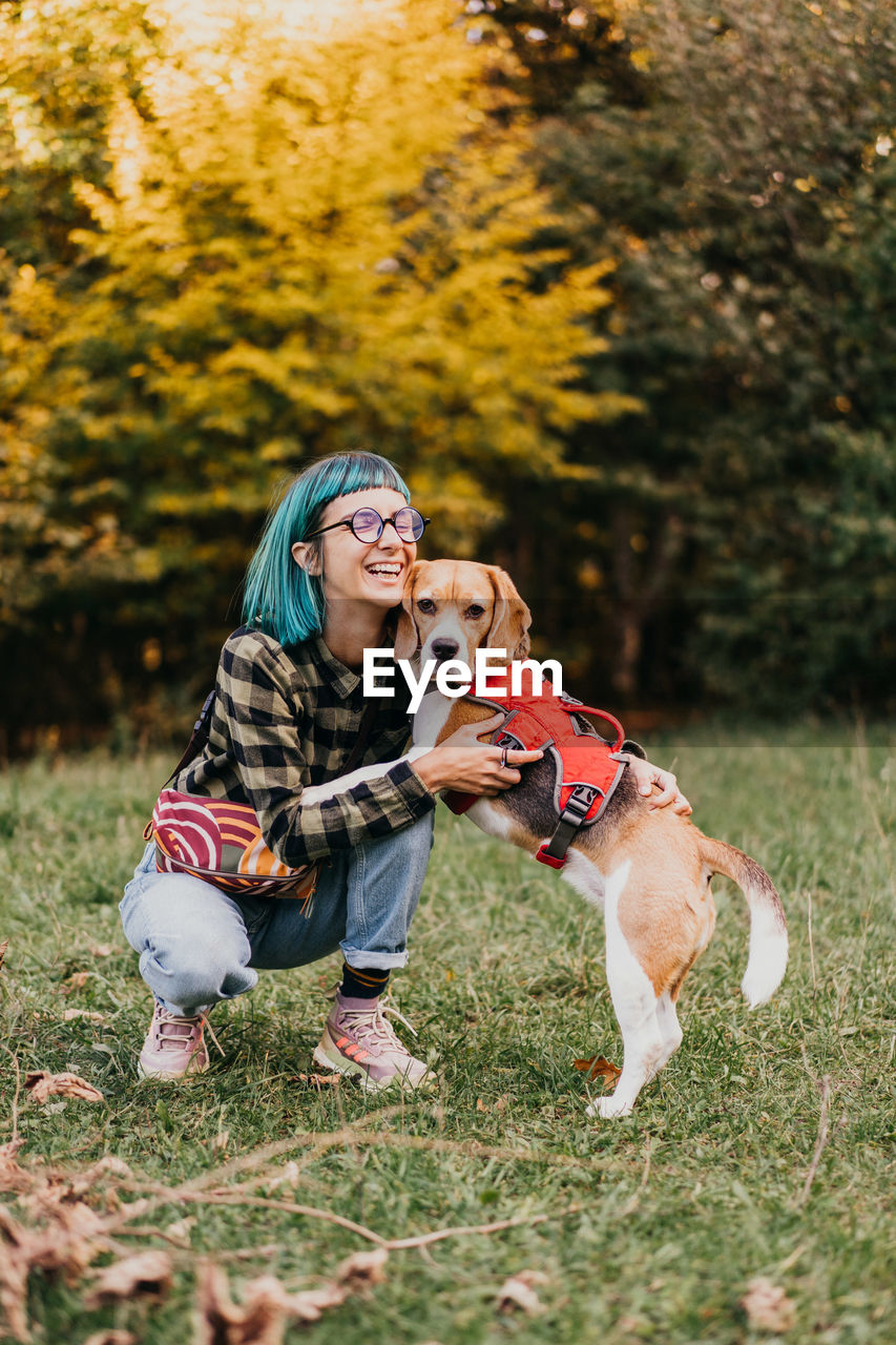 Portrait of young woman with dog on grassy field