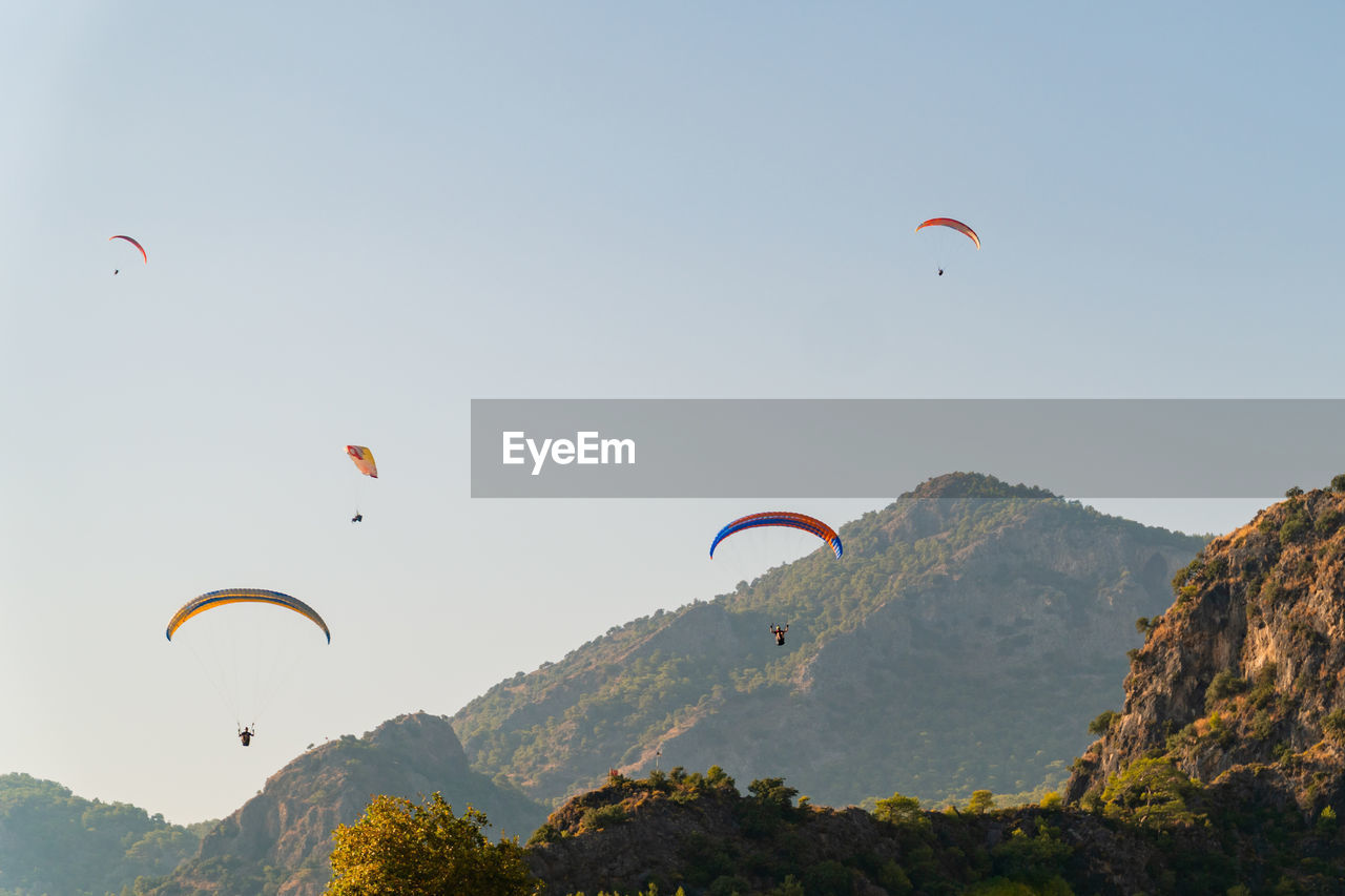 Fly away - paragliders soar and descend in a valley near fethiye in turkey.