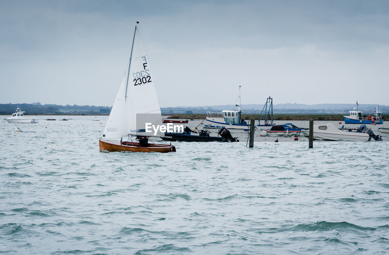 BOAT SAILING ON SEA AGAINST SKY