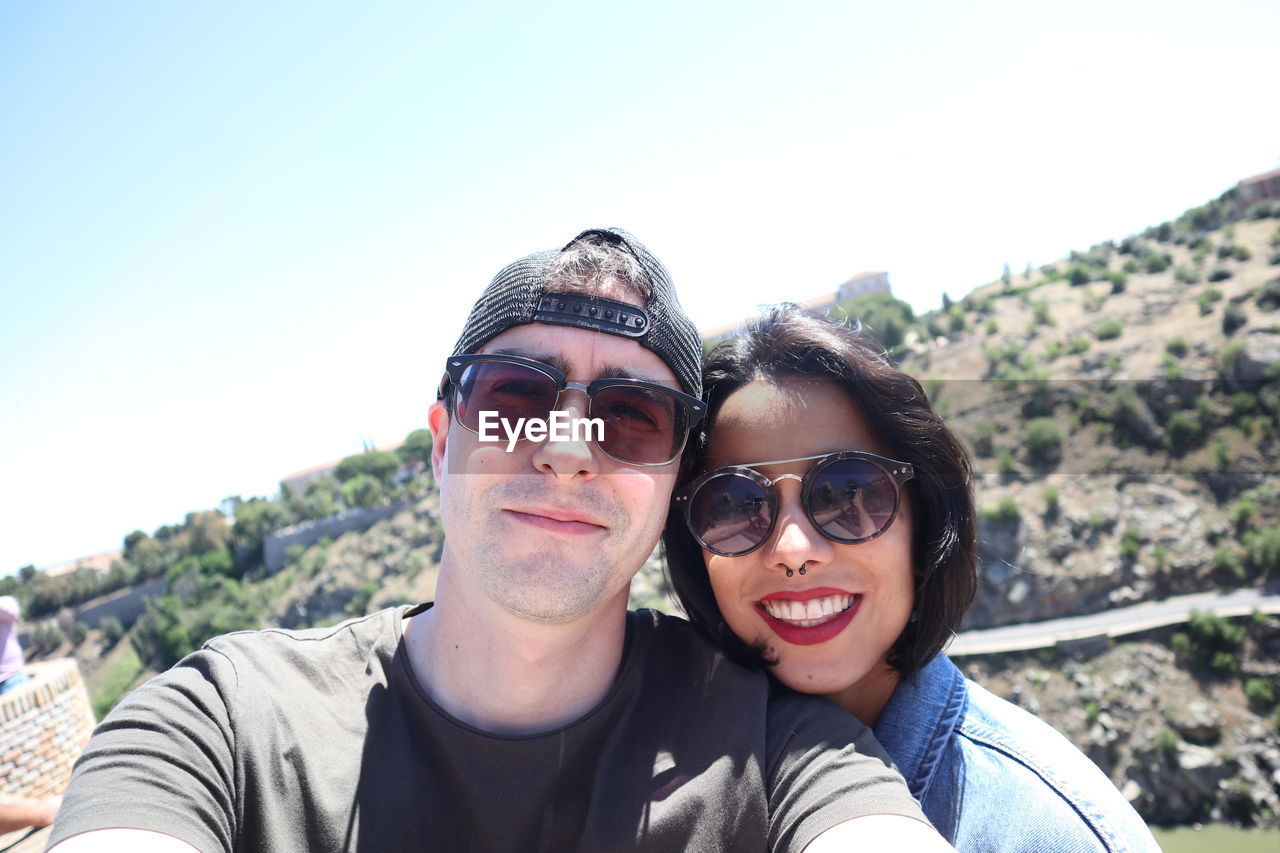 Portrait of smiling man wearing sunglasses against sky