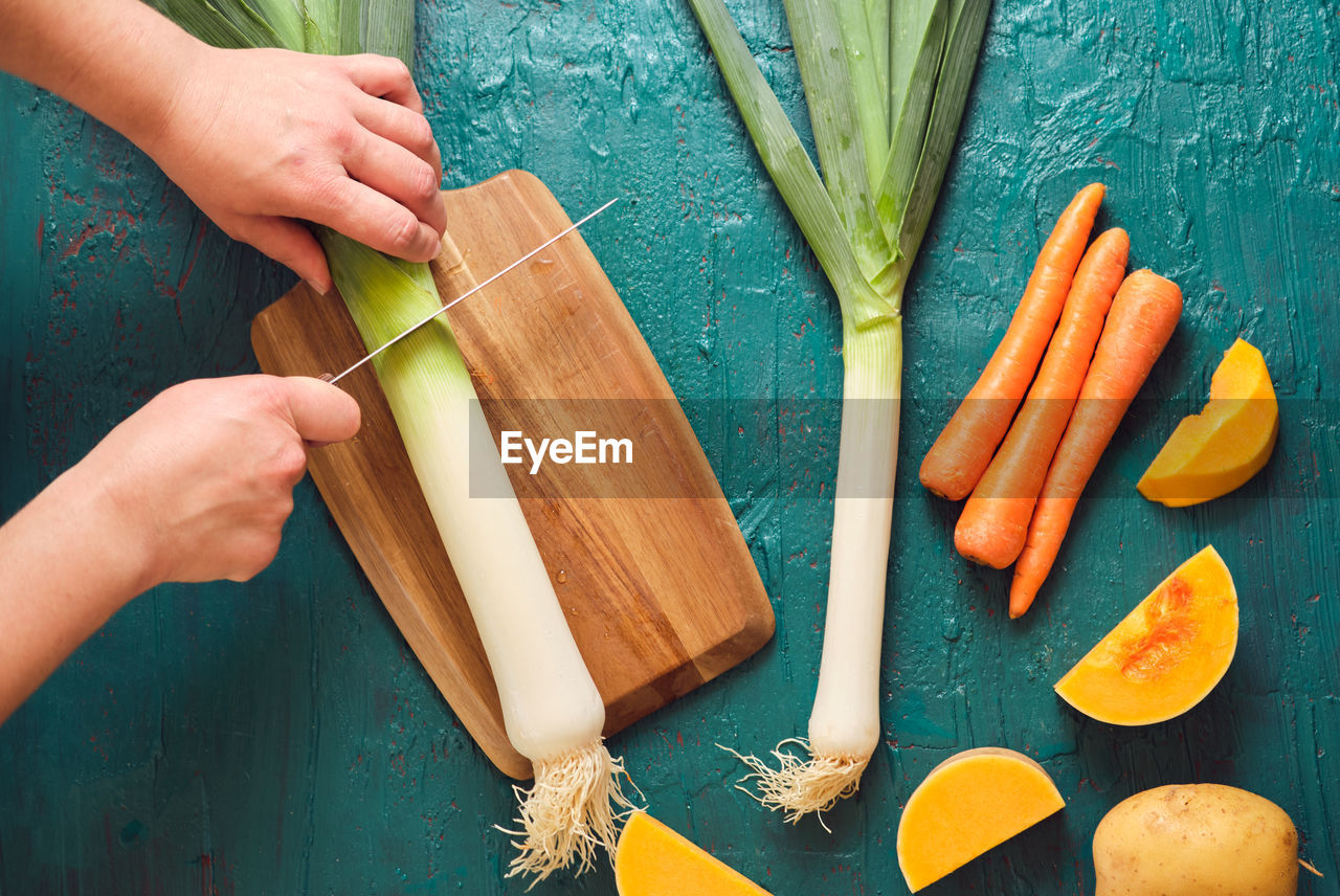 Hands cutting leeks to prepare pureed vegetables