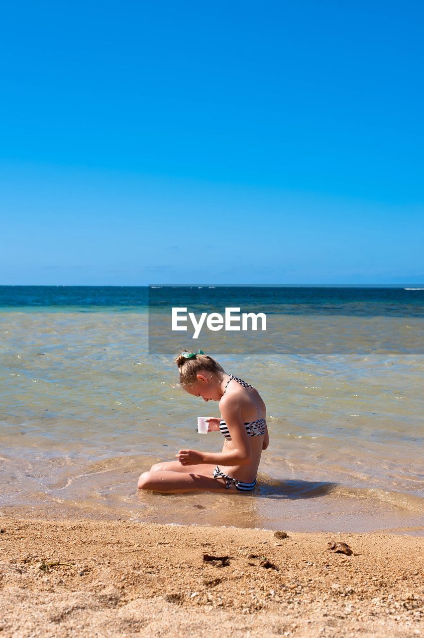 WOMAN ON BEACH AGAINST CLEAR BLUE SKY