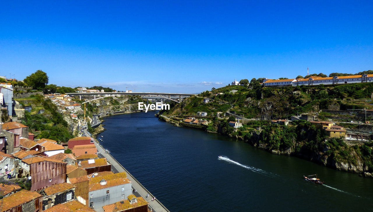 HIGH ANGLE SHOT OF TOWNSCAPE BY SEA AGAINST CLEAR BLUE SKY