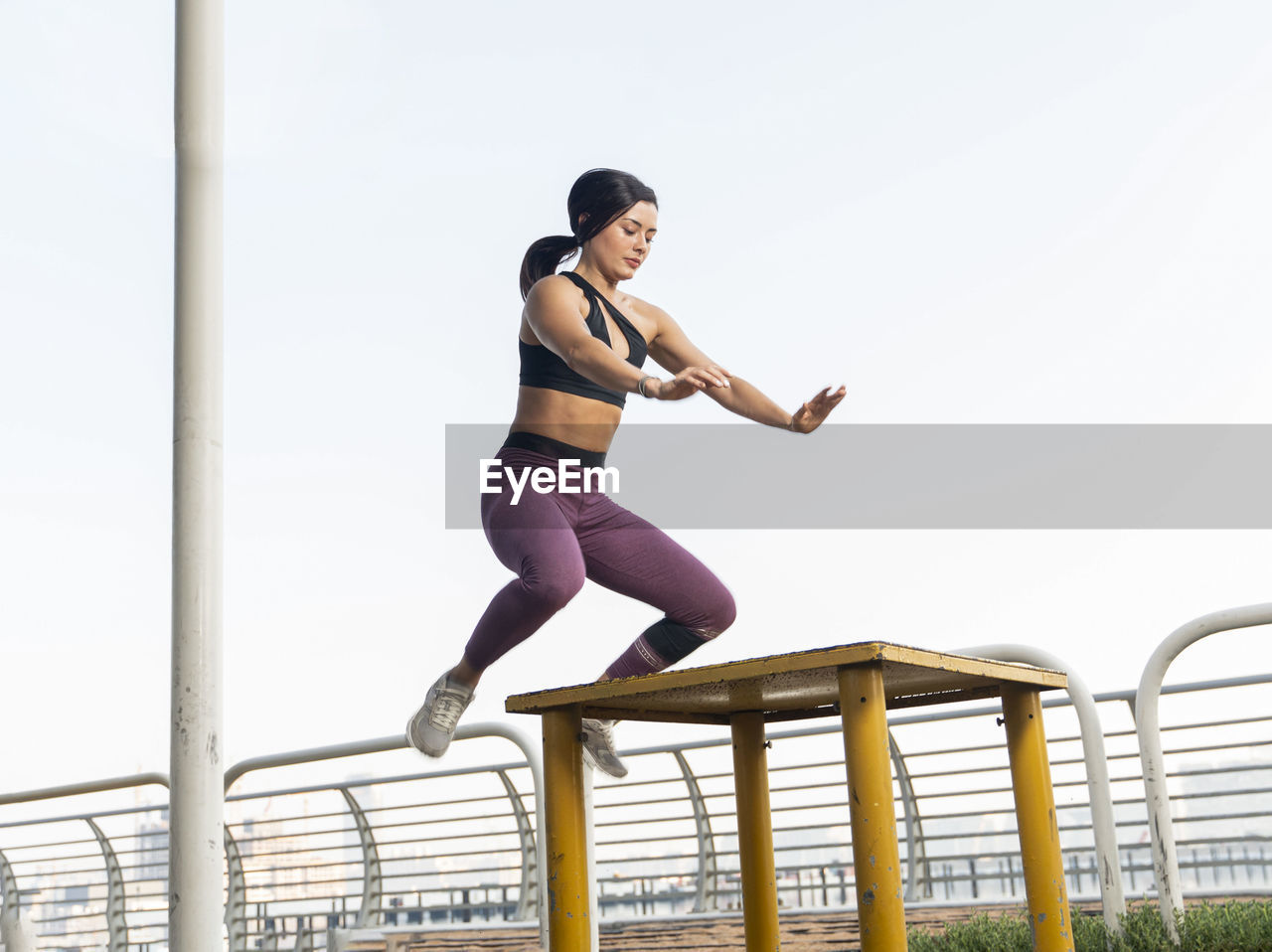 FULL LENGTH OF WOMAN SITTING ON RAILING