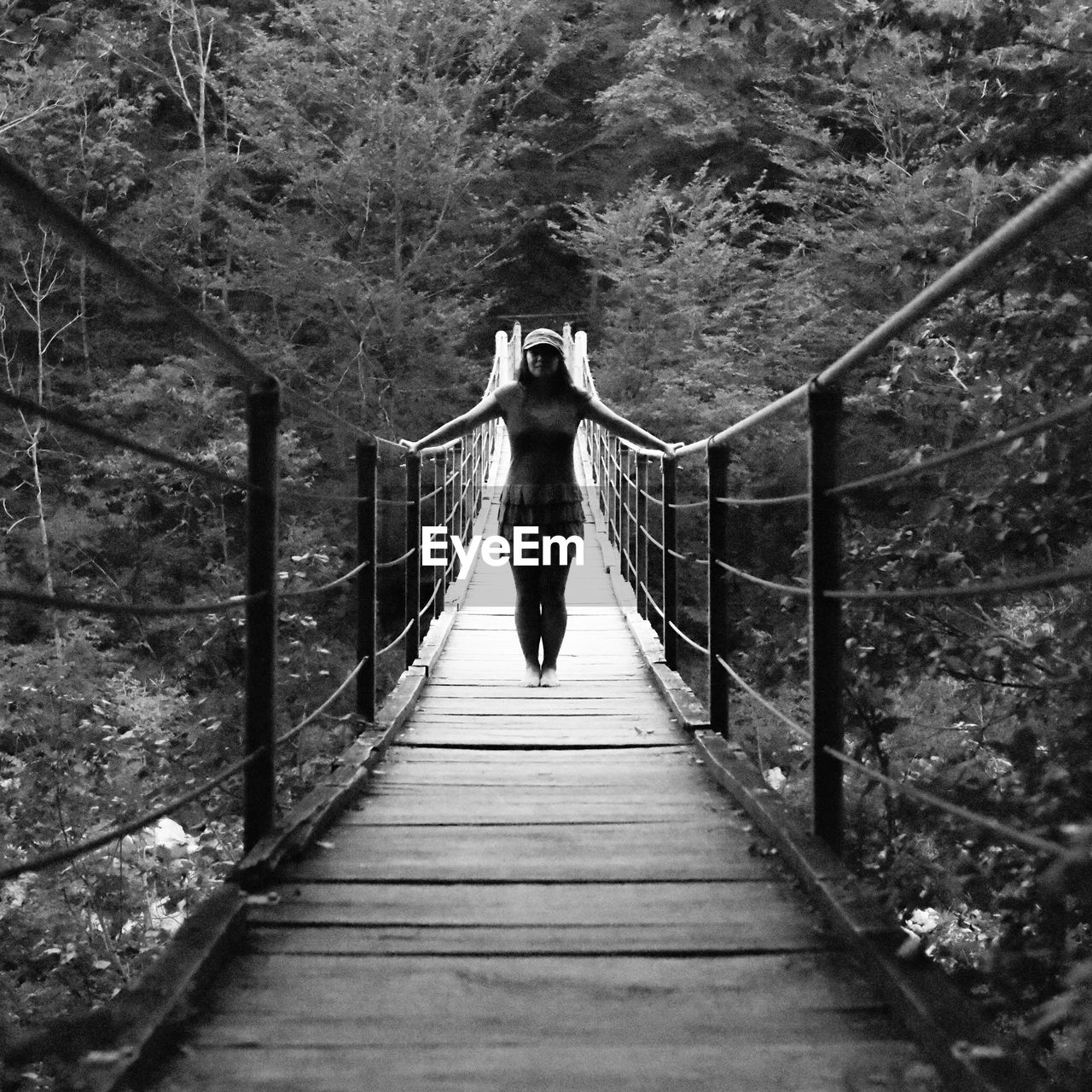 Woman standing on bridge against trees