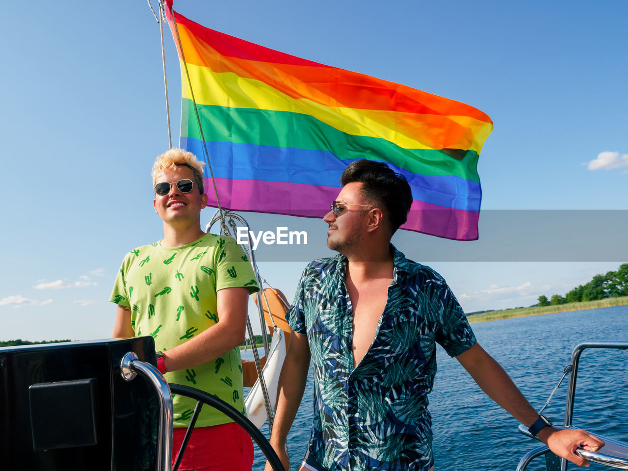 Gay couple have a vacations on a sailing yacht with lgbt rainbow flag