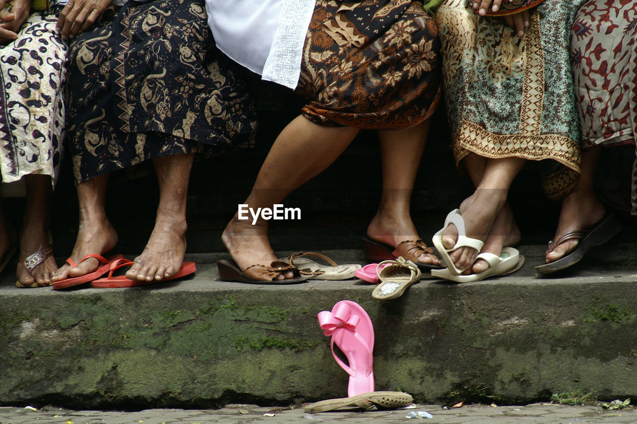 Low section of women standing by sandal