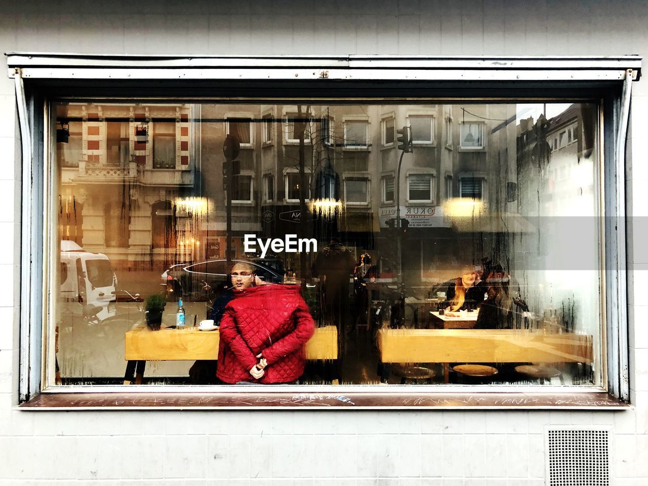 REAR VIEW OF WOMAN SITTING ON WINDOW