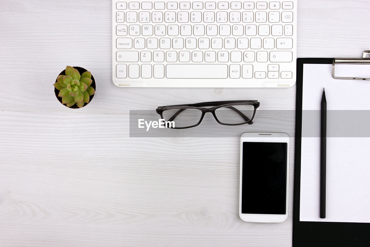 Business concept. work from home. office flatlay with white keyboard, reading glasses, and notebook.