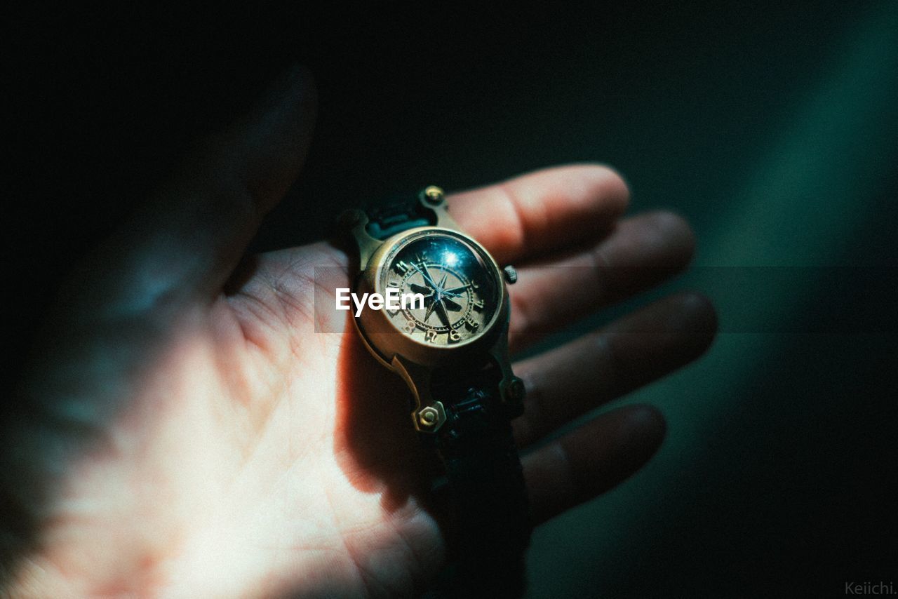 Cropped hand holding watch in darkroom