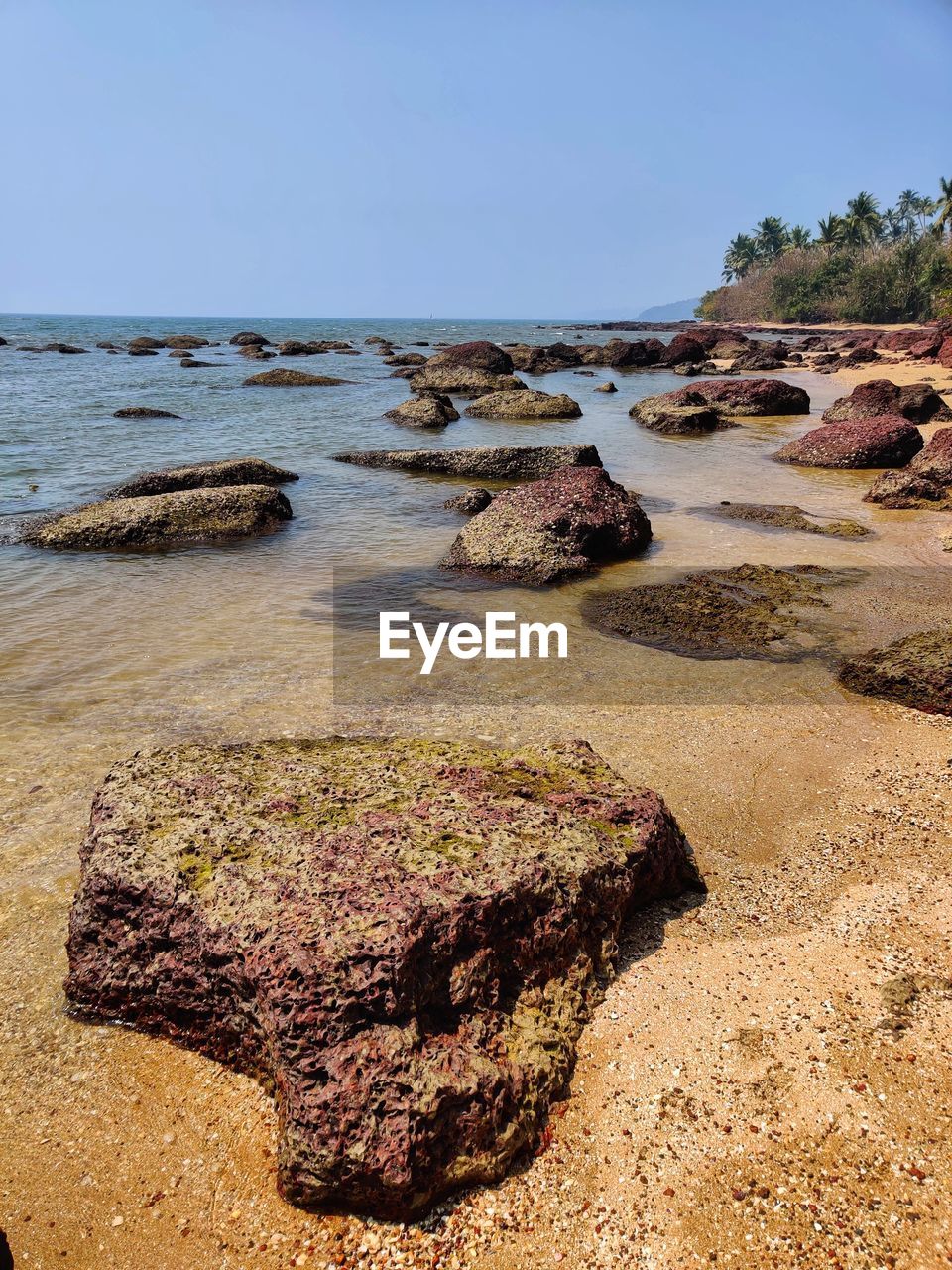 ROCKS ON BEACH AGAINST CLEAR SKY