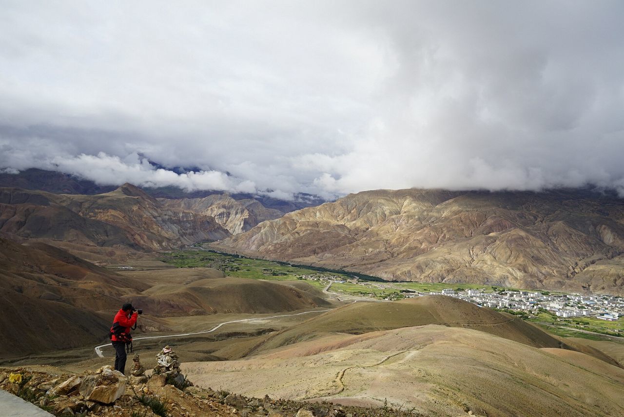 Man photographing mountains against cloudy sky