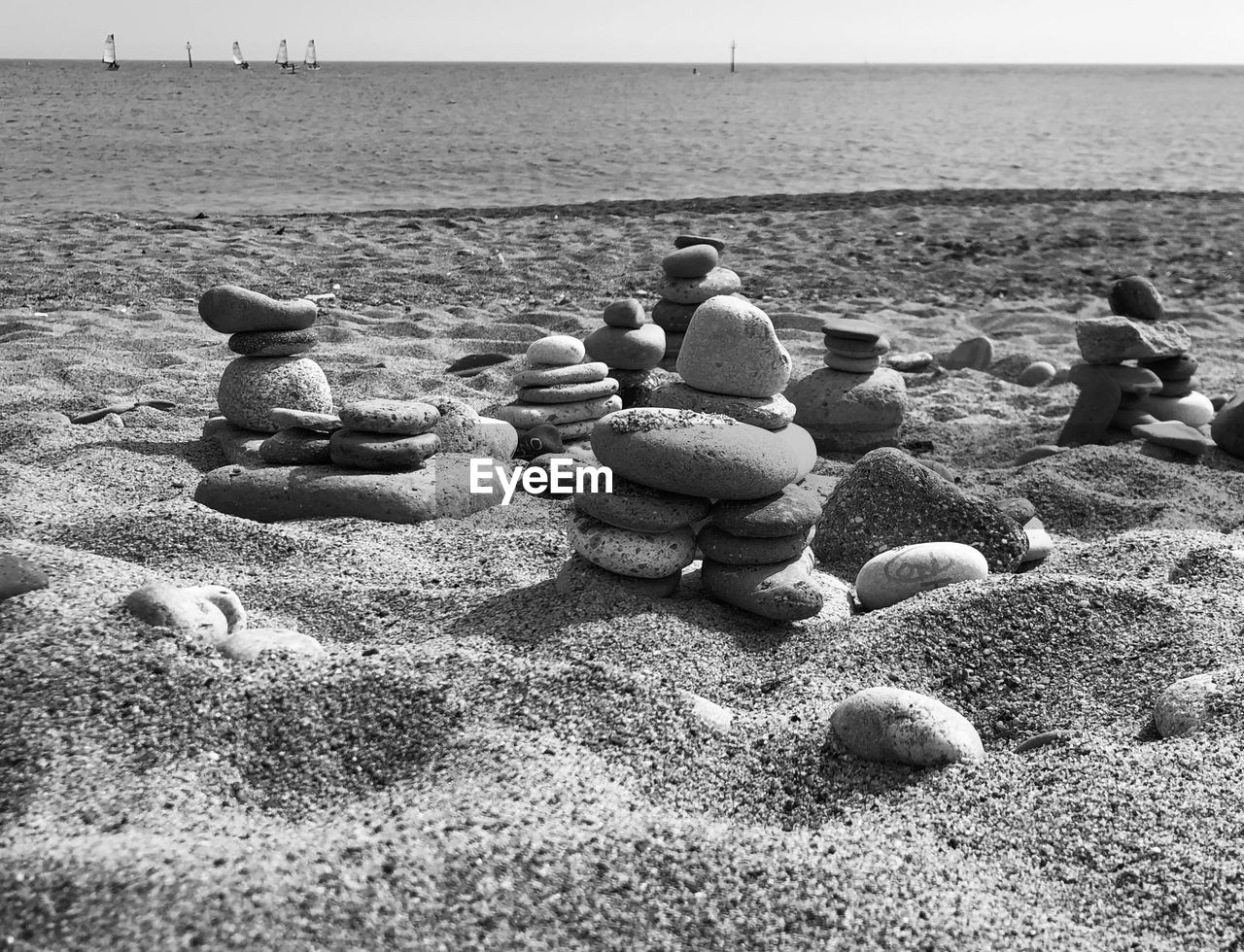 STACK OF PEBBLES ON SAND AT BEACH