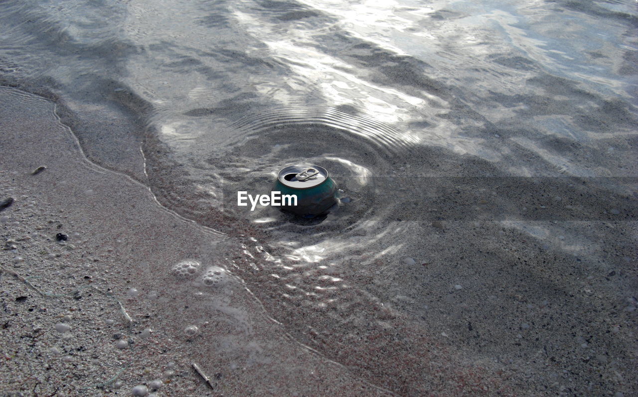 High angle view of abandoned drink can on shore