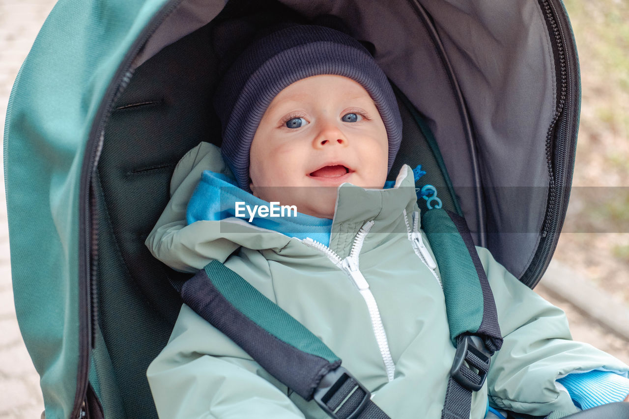 child, childhood, portrait, baby carriage, blue, one person, clothing, baby, looking at camera, cute, person, emotion, men, toddler, nature, hood - clothing, day, happiness, innocence, hood, outdoors, leisure activity, winter, smiling, front view, fun, baby stroller