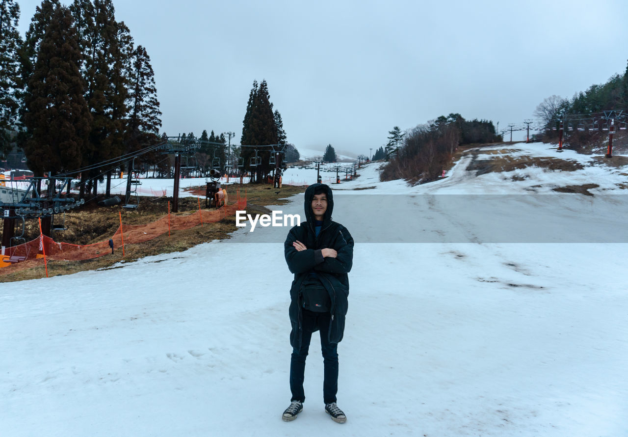 Portrait of man standing in snow against sky